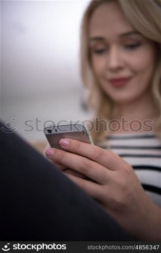 young happy woman sitting on sofa with mobile phone at luxury home