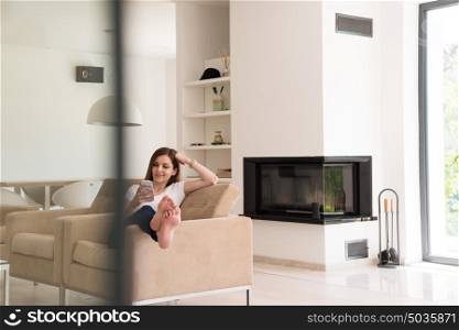 young happy woman sitting on sofa with mobile phone at luxury home