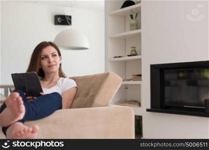 young happy woman sitting on sofa with tablet computer at luxury home