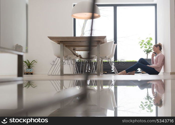 young happy woman sitting on the floor and using mobile phone at home