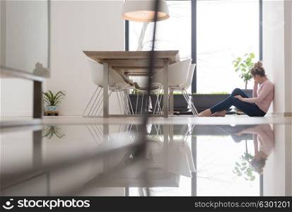 young happy woman sitting on the floor and using mobile phone at home