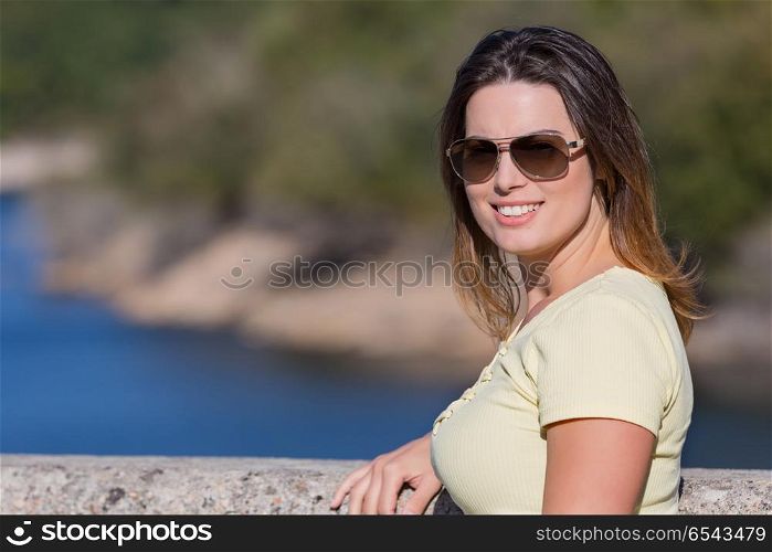 Young happy woman sitting on the rock mountain, relaxing and enjoying the lake at Geres, Portuguese National Park. girl enjoying the lake