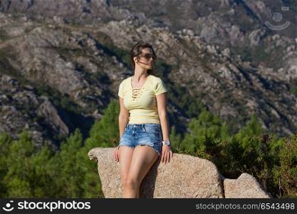 Young happy woman sitting on the rock mountain, relaxing and enjoying the valley view at Geres, Portuguese National Park. girl enjoying