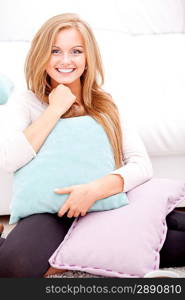 young happy woman smiling and hugging pillow at home