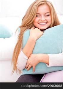 young happy woman smiling and hugging pillow at home