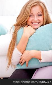 young happy woman smiling and hugging pillow at home
