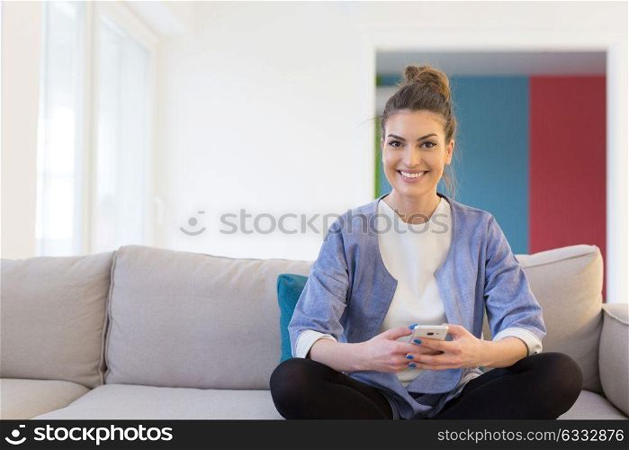 young happy woman using mobile phone on sofa at luxury home