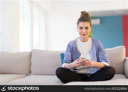 young happy woman using mobile phone on sofa at luxury home