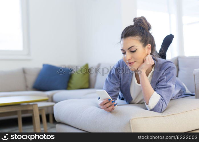 young happy woman using mobile phone on sofa at luxury home