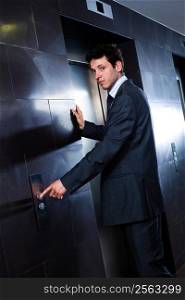 Young hapy businessman standing at office in front of elevator.
