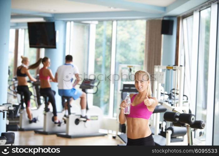 young healthy blonde woman in fitness gym drink water