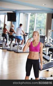 young healthy blonde woman in fitness gym drink water