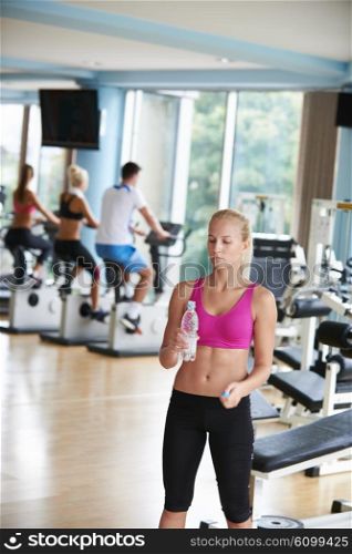 young healthy blonde woman in fitness gym drink water