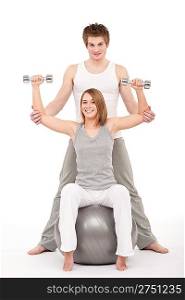 Young healthy couple training with weights and fitness ball on white