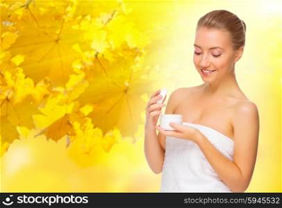 Young healthy girl with body cream jar on autumn background