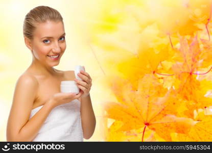 Young healthy girl with body cream on autumnal background