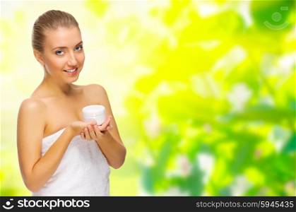 Young healthy girl with body cream on floral spring background