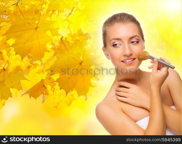 Young healthy girl with makeup brush on autumnal background