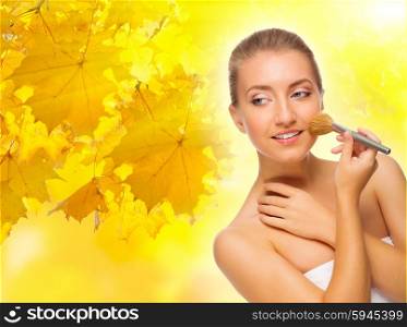 Young healthy girl with makeup brush on autumnal background