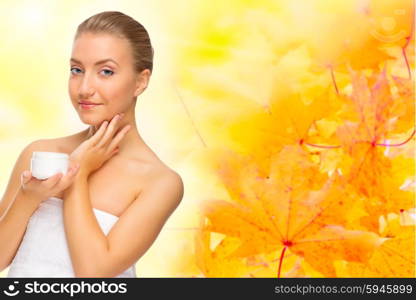 Young healthy woman with body cream on autumnal background