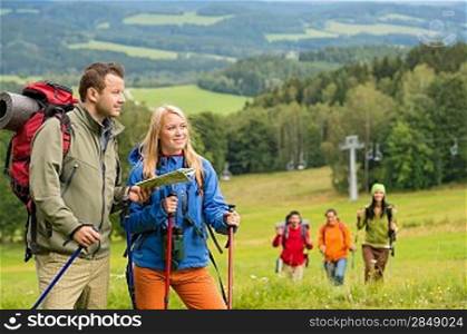 Young hiker friends reading map in natural landscape