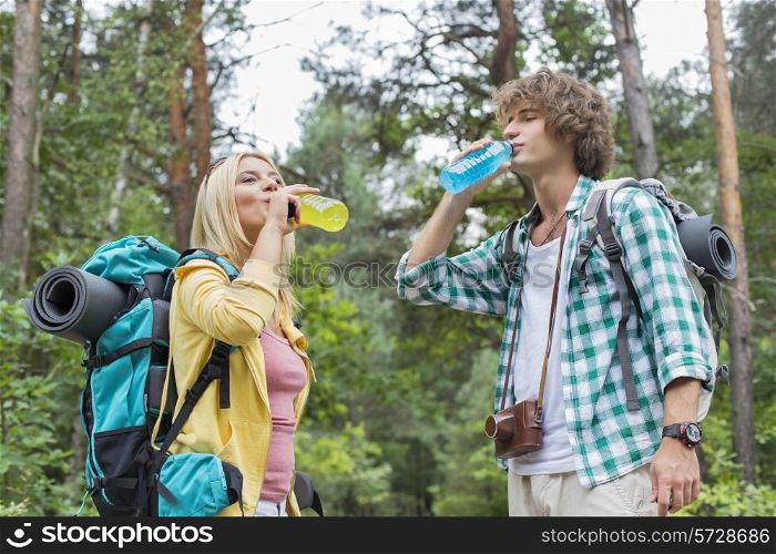 Young hiking couple drinking energy drinks in forest