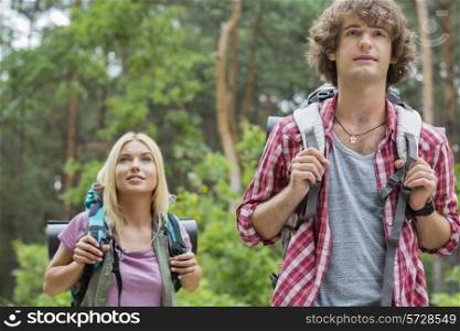 Young hiking couple looking away in forest