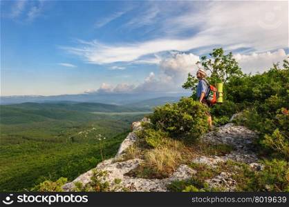 Young hiking man in the rays of sunset, standing at the top of Tope Kermen cliff, Crimea, Ukraine