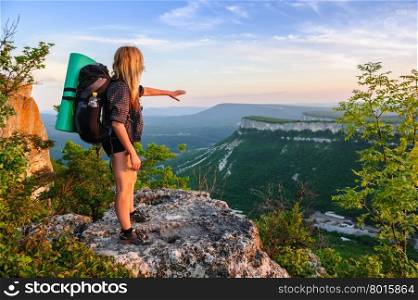 Young hiking woman in the rays of sunset, standing at the top of Tope Kermen, Crimea, Ukraine