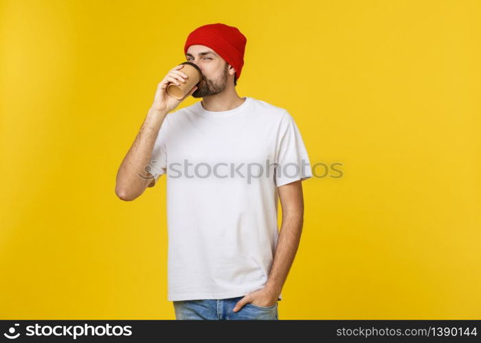 Young hipster man holding a cup of coffee isolated over yellow background. Young hipster man holding a cup of coffee isolated over yellow background.