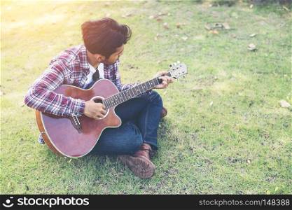 Young hipster man practiced guitar in the park,happy and enjoy p. Young hipster man practiced guitar in the park,happy and enjoy playing guitar.