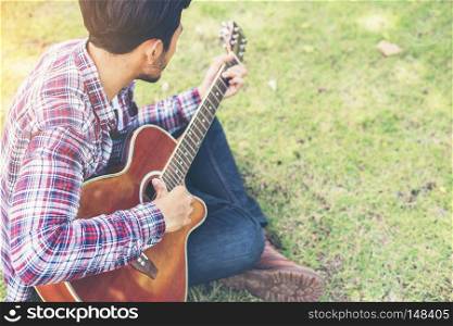 Young hipster man practiced guitar in the park,happy and enjoy p. Young hipster man practiced guitar in the park,happy and enjoy playing guitar.