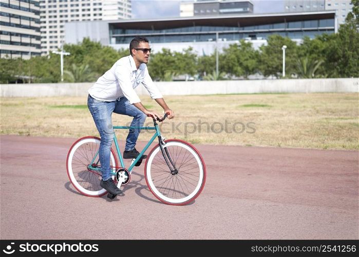 young hipster man riding fixed gear bike on city street