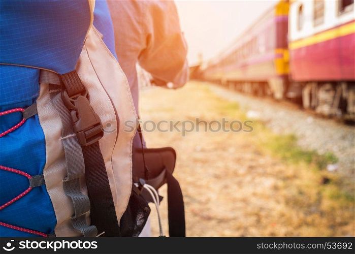 Young hipster man with a backpack ready to embark on a journey by train, Trendy guy standing looking away.