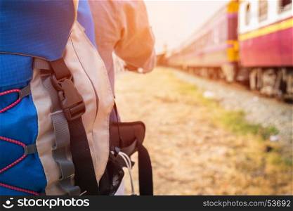 Young hipster man with a backpack ready to embark on a journey by train, Trendy guy standing looking away.