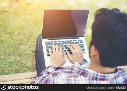 Young hipster man work on computer at the park in a sunny day.