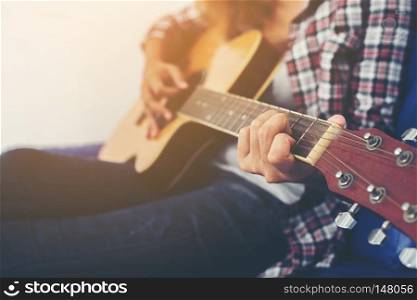 Young hipster woman playing a guitar.