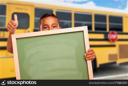 Young Hispanic Boy with Blank Chalkboard Near School Bus.