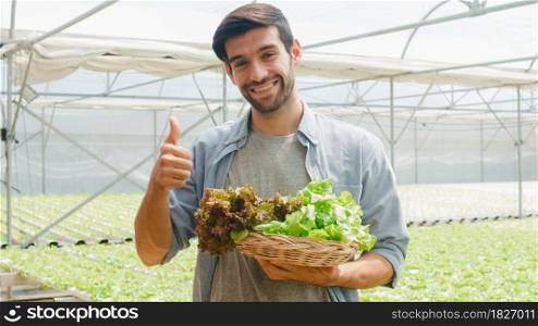 Young hispanic businessman farmer with good quality product selling plant and vegetable looking at camera at organic farm in greenhouse garden, Farm innovation technology concept.