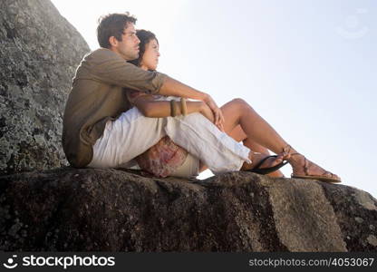 Young hispanic couple sitting on rocks