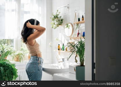 Young hispanic woman dancing with headphones in bathroom. Body positivity, confort home zone, wellness and lifestyle. Young hispanic woman dancing with headphones in bathroom