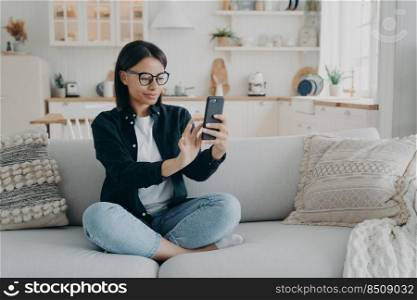 Young hispanic woman has video call, relaxing and surfing through internet with mobile phone. Girl is texting and smiling, receiving messages on cellphone. Chatting, gadget and application using.. Young hispanic woman has video call, relaxing and surfing through internet with cellphone.