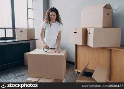 Young hispanic woman is packing containers with sticky tape. Happy mover is wrapping cardboard boxes with packing tape. Moving service worker preparing boxes for shipping and storage.. Young hispanic woman is packing containers with sticky tape. Happy mover wrapping cardboard boxes.