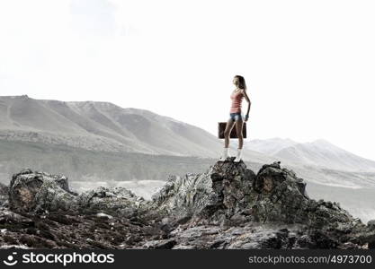 Young hitchhiking traveler. Young pretty girl walking with her retro suitcase in hand