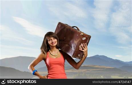 Young hitchhiking traveler. Young pretty girl with her retro suitcase on shoulder
