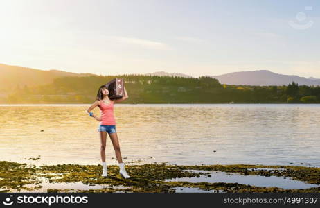 Young hitchhiking traveler. Young pretty girl with her retro suitcase on shoulder