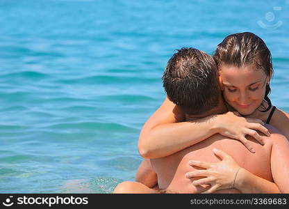 young hot woman sitting astride man in sea near coast