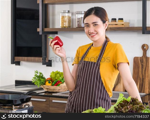 Young housewife chooses vegetables from the prepared basket for cooking. Morning atmosphere in a modern kitchen