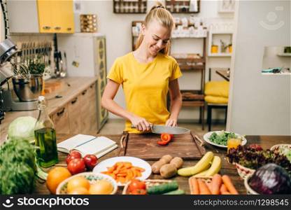 Young housewife cooking on the kitchen, healthy eco food. Vegetarian diet, fresh vegetables and fruits on wooden table. Young housewife cooking on the kitchen, eco food