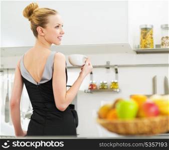 Young housewife drinking coffee in kitchen